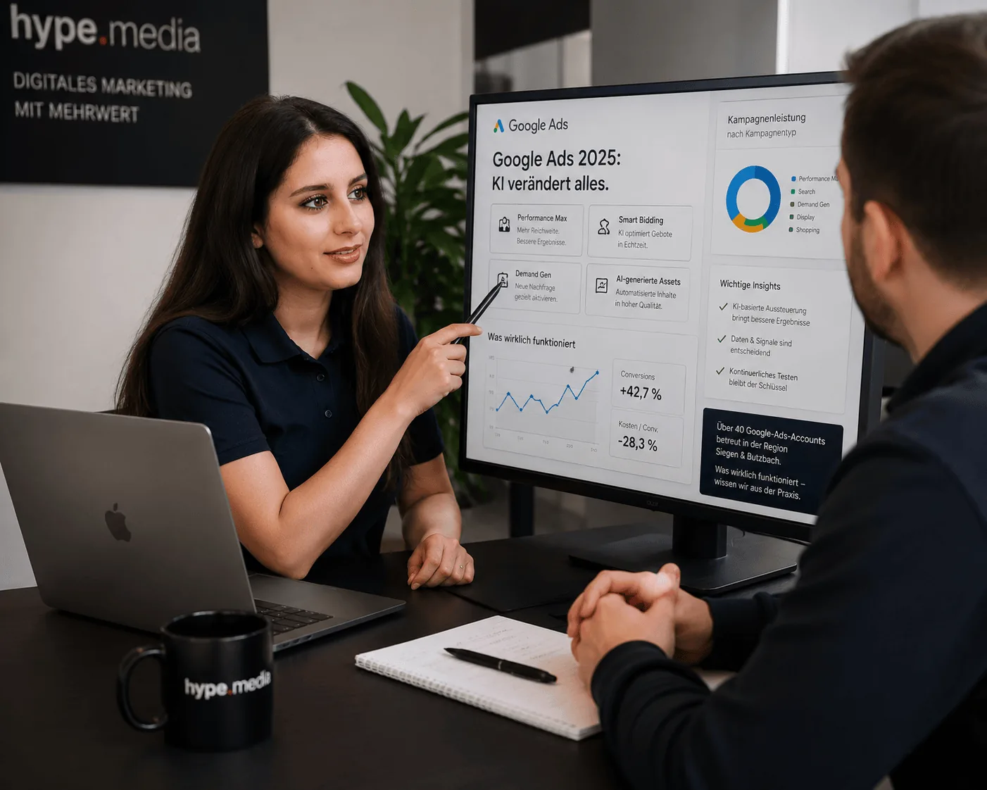 Beraterin erläutert einem Kunden eine Auswertung zu Suche und Anzeigen am Monitor