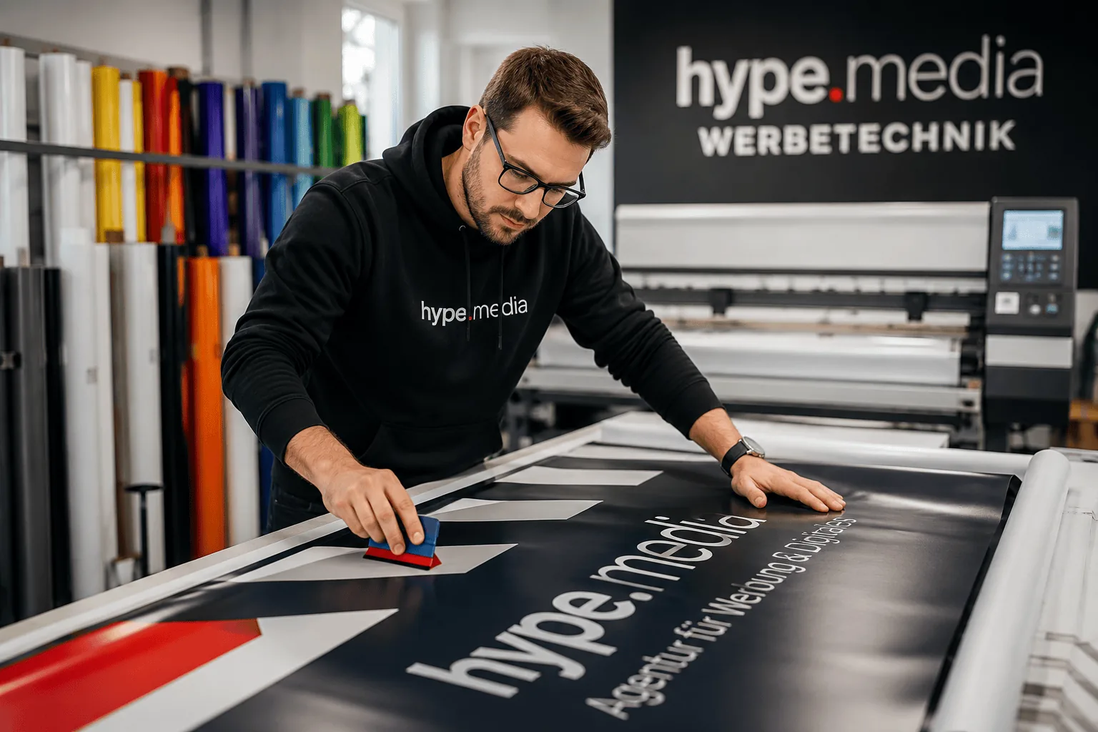 Werbetechniker kaschiert einen großformatigen Druck mit hype.media-Schriftzug