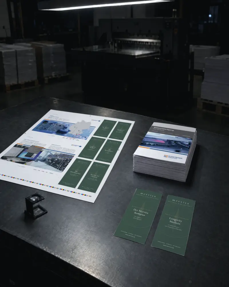 Druckbogen, Imagebroschüren und Infokarten von Kunden auf dem Abstimmtisch der Druckerei