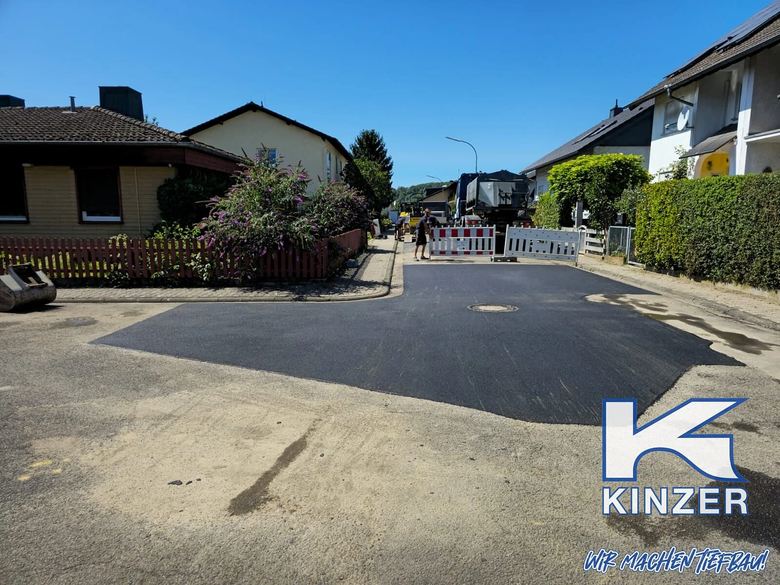 Frisch asphaltierte Straße in einem Wohngebiet, Bild mit Kinzer-Wasserzeichen
